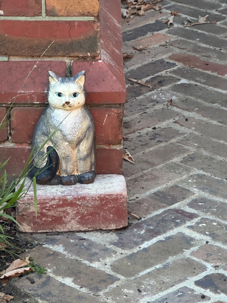 a statue of a cat sitting on top of a brick wall